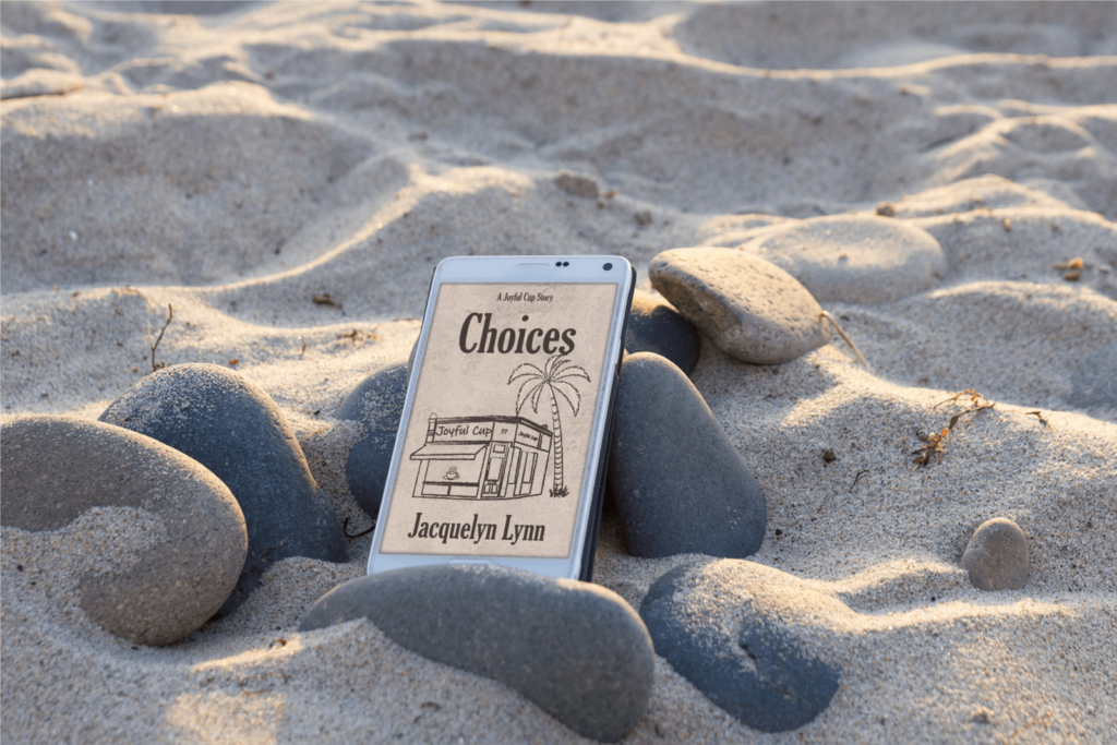 Rocks on sand with Choices by Jacquelyn Lynn on an ereader