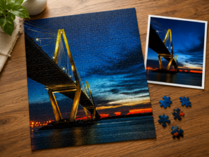 Completed jigsaw puzzle of a dramatic bridge at dusk beside the original photograph on a wooden table